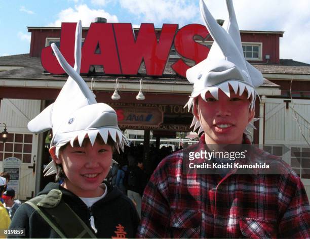 Visitors wear shark-shaped hats, inspired by Steven Spielberg's film series "Jaws," at Universal Studios at the grand opening March 31, 2001 in...