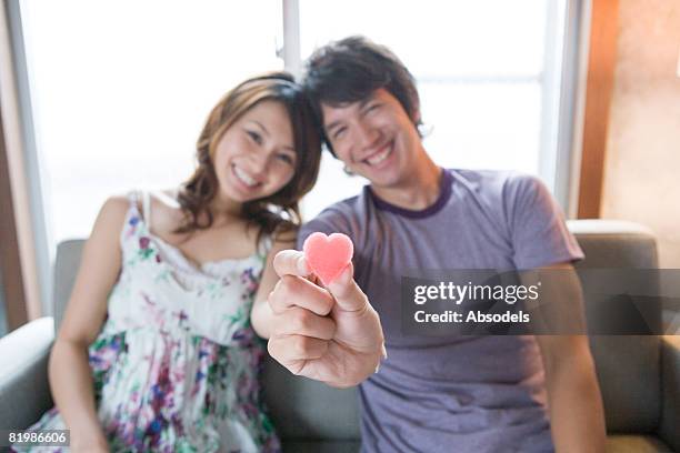 young man and woman holding heart shaped candy, smiling - valentine japan stock pictures, royalty-free photos & images