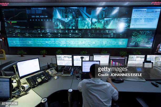 This picture taken on July 11, 2017 shows a man working at the central command centre of the Shanghai metro system. Deep underneath Shanghai, workers...