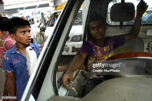 Nadim , looks at the camera as he was waiting for passengers on Thursday, July 2017 in Dhaka, Bangladesh. He has been working as a driver's assistant...