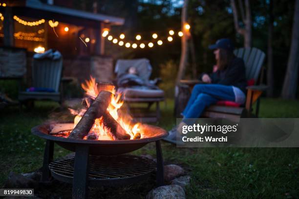 mother and her daughter warm near campfire late evening  at a beatiful canadian chalet - cosy family stock pictures, royalty-free photos & images