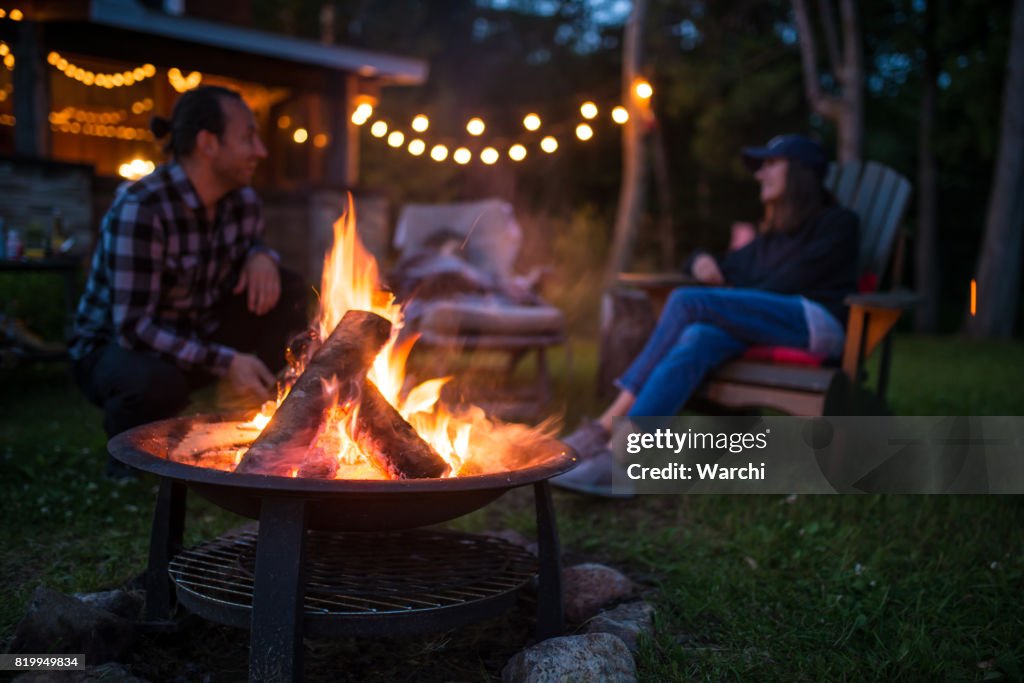 年輕的家庭氣候變暖在篝火附近傍晚在美麗的加拿大木屋
