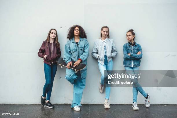 fyra tonåriga flickor står framför betongväggen - luta fysisk ställning bildbanksfoton och bilder