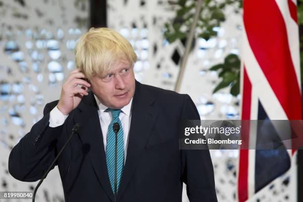 Boris Johnson, U.K. Foreign secretary, adjusts his ear piece as he listens to Fumio Kishida, Japan's foreign minister, not pictured, delivering a...