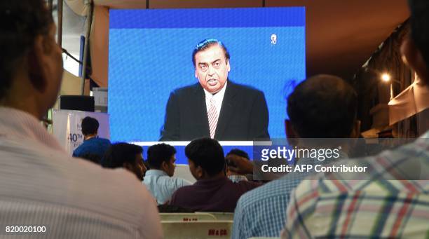 Shareholders watch India's richest man and oil-to-telecom conglomerate Reliance Industries chairman Mukesh Ambani speak during the company's 40th AGM...