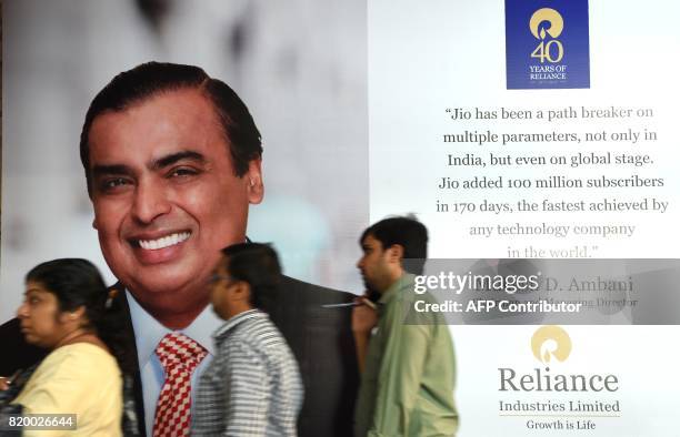 Shareholders walk past a poster of India's richest man and oil-to-telecom conglomerate Reliance Industries chairman Mukesh Ambani during the...