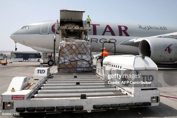 Workers offload cargo from a Qatar Airways Cargo plane at the Hamad International Airport in Doha on July 20, 2017. / AFP PHOTO / STRINGER