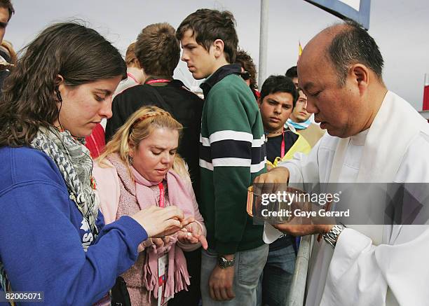 Pilgrims line up as they receive Holy Communion from a priest as His Holiness Pope Benedict XVI holds his Final Mass of World Youth Day at Randwick...