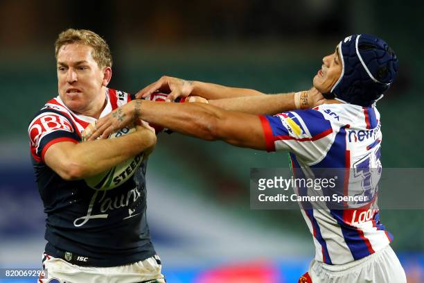 Mitchell Aubusson of the Roosters fends off Sione Mata'utia of the Knights during the round 20 NRL match between the Sydney Roosters and the...