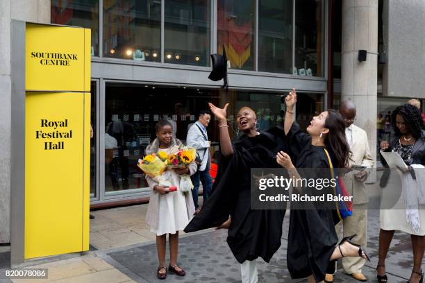 Lady graduates fling their rented mortarboard hats into the air after their graduation eremony, in celebration of their university academic...