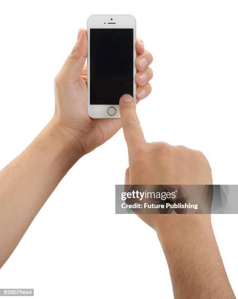 Detail of hands holding and pressing the touchscreen of an Apple iPhone SE smartphone, taken on April 7, 2016.