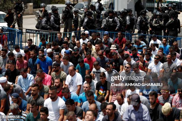 Israeli security forces stand guard as Palestinian worshippers pray outside Jerusalem's Old City in front of the Al-Aqsa mosque compound after...
