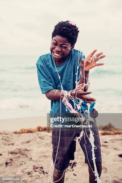 young african american boy being string sprayed on the beach. - party string stock pictures, royalty-free photos & images