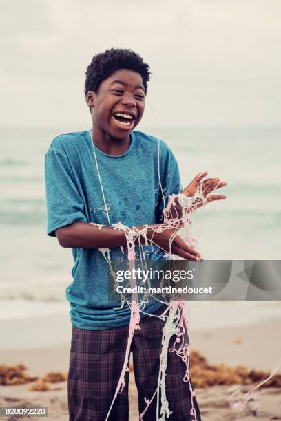 young african american boy being string sprayed on the beach. - party string stock pictures, royalty-free photos & images