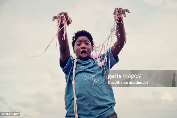 young african american boy being string sprayed on the beach. - party string stock pictures, royalty-free photos & images