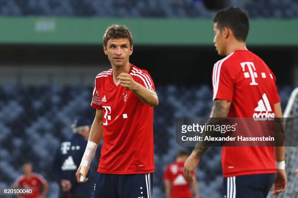 Thomas Mueller of FC Bayern Muenchen talks to his team mate James Rodriguez during a training session at Shenzhen Universiade Sports Centre during...