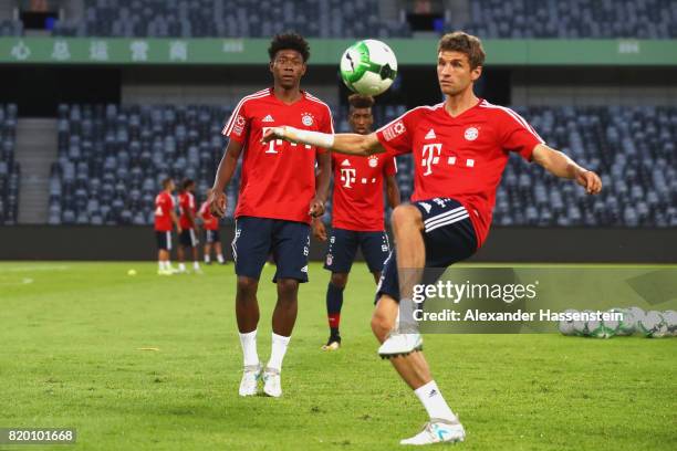 Thomas Mueller of FC Bayern Muenchen battles for the ball with his team mate David Alaba during a training session at Shenzhen Universiade Sports...