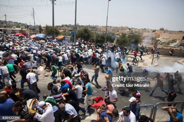 Palestinian worshippers run for cover from teargas, fired by Israeli forces, following prayers in Ras el-Amud Area outside the Old City on July 21,...