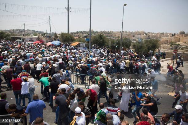 Palestinian worshippers run for cover from teargas, fired by Israeli forces, following prayers in Ras el-Amud Area outside the Old City on July 21,...