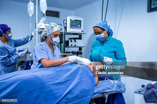 anestesista in procedura di risveglio con paziente femmina dopo la procedura chirurgica di naso e liposuzione. - intubation foto e immagini stock