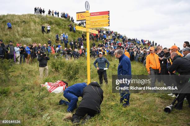 Officials remove a direction sign for Rory McIlroy of Northern Ireland on the 15th hole during the second round of the 146th Open Championship at...