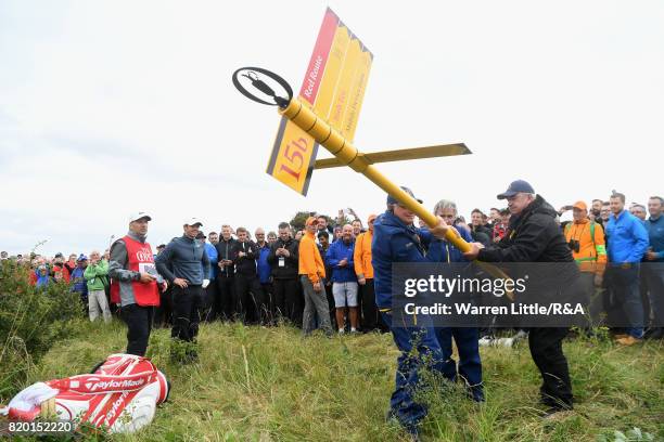 Officials remove a direction sign for Rory McIlroy of Northern Ireland on the 15th hole during the second round of the 146th Open Championship at...