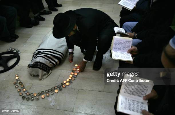 An Ultra-Orthodox Jew light candles as others pray before the start of the funeral of Rabbi Yitzhak Kaduri, wrapped in the Talit or religious shawl,...
