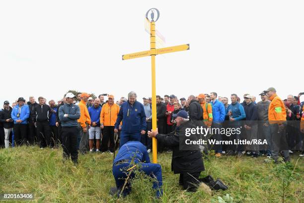 Rules Official John Paramor helps remove a signpost to allow Rory McIlroy of Northern Ireland to play on the 15th hole during the second round of the...