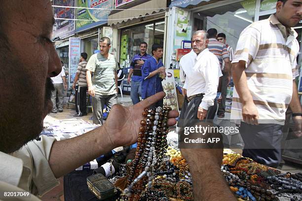 Abu Ahmad, a prayer bead stringer, who lost his left thumb during the 1980-1988 Iran-Iraq war, displays prayer beads for sale at his stall in central...