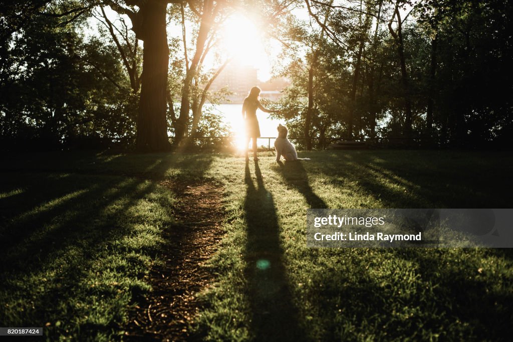 Silhouette of a woman and a dog looking at each other at sunset