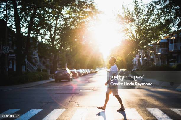 a mature man crossing a street at sunset - pedestrian crossing man stock pictures, royalty-free photos & images