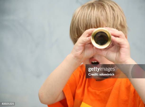 a cute 4 1/2 year old boy looking though a telescope with a surprised expression. - 望遠鏡 ストックフォトと画像