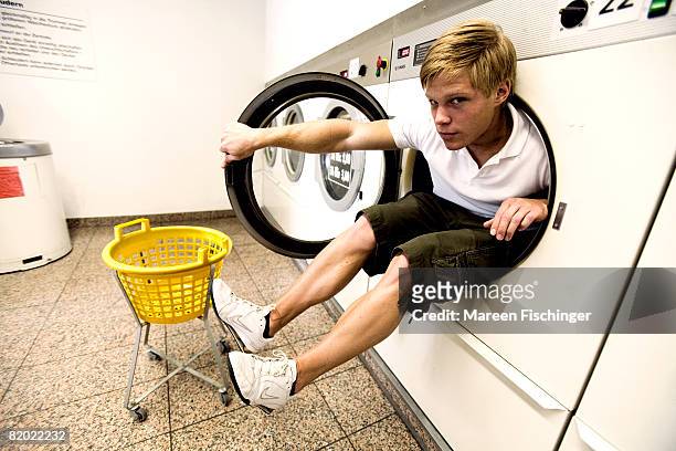 boy (16-17 years) playing in laundromat, portrait - 16 17 years photos fotografías e imágenes de stock
