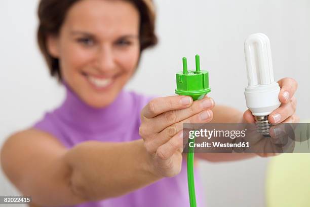 woman holding green plug and bulb - energy efficient lightbulb stock-fotos und bilder