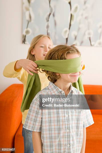 boy (6-7) and girl (8-9) playing blind man's bluff - blinddoek stockfoto's en -beelden