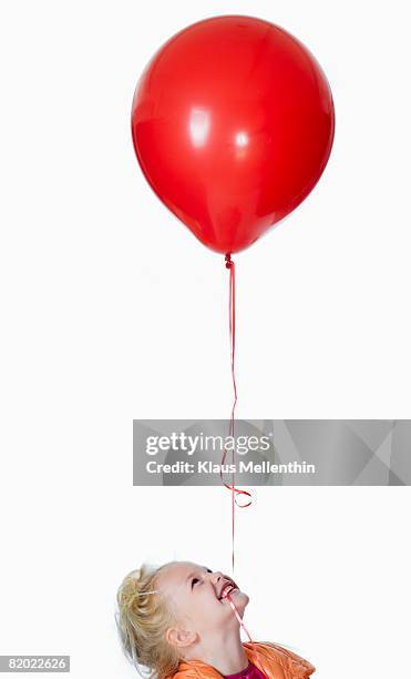 girl (8-9) with red balloon in mouth, portrait - child balloon studio photos et images de collection