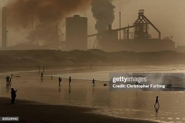 Locals and children play on the surf at high tide on Redcar beach in the shadow of the Corus Steelworks in Teeside, on July 21 in Middlesborough,...
