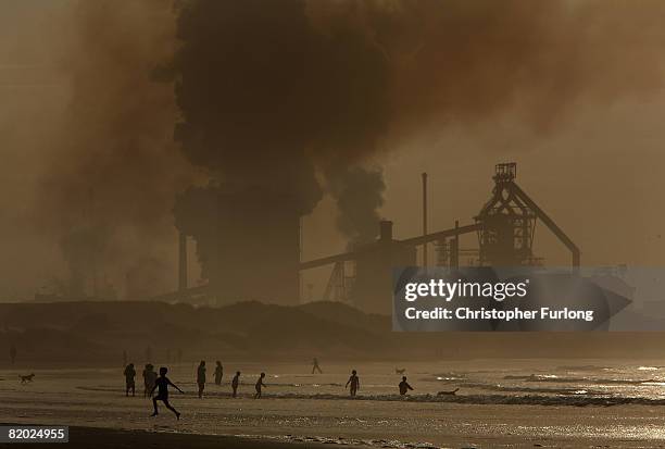 Locals and children play on the surf at high tide on Redcar beach in the shadow of the Corus Steelworks in Teeside, on July 21 in Middlesborough,...