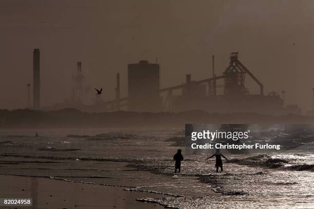 Locals and children play on the surf at high tide on Redcar beach in the shadow of the Corus Steelworks in Teeside, on July 21 in Middlesborough,...