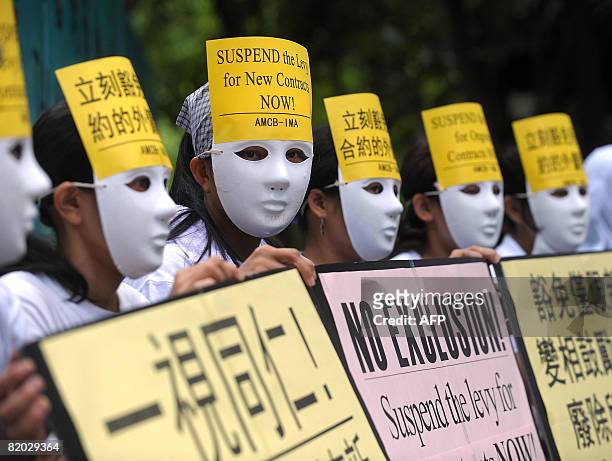 Foreign domestic helpers, wearing masks to conceal their identities from their employers, demonstrate outside the Government Central Offices in Hong...