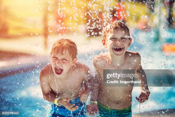 kleine jongens plezier in waterpark - family in rain stockfoto's en -beelden