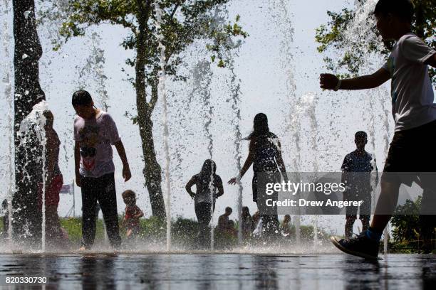 Children play in a fountain in Battery Park in Lower Manhattan, July 21, 2017 in New York City. Temperatures are soaring into the 90s again on Friday...