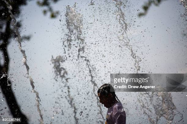 Boy cools off in a fountain in Battery Park in Lower Manhattan, July 21, 2017 in New York City. Temperatures are soaring into the 90s again on Friday...