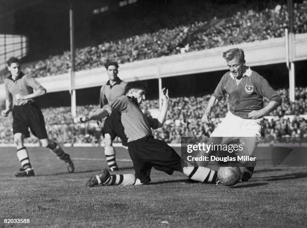 Wolves centre half Bill Shorthouse makes a sliding tackle on Portsmouth's Jack Froggatt during the FA Charity Shield match at Highbury Stadium,...