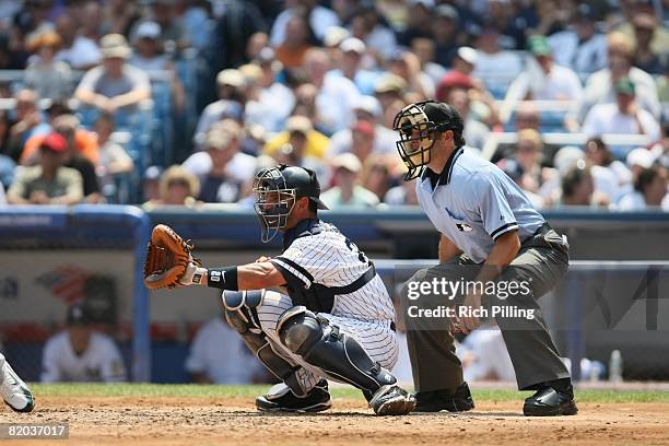 Jorge Posada of the New York Yankees and home-plate umpire James Hoye await the pitch during the game against the Oakland Athletics at Yankee Stadium...