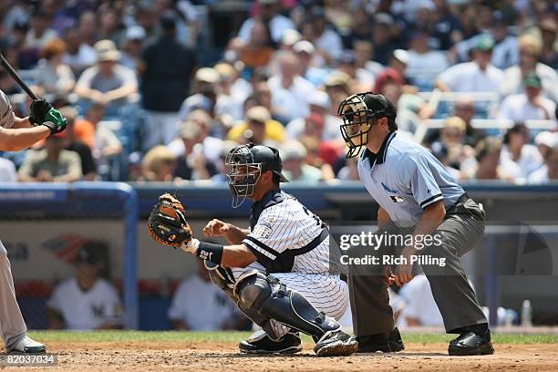 Jorge Posada of the New York Yankees and home-plate umpire James Hoye await the pitch during the game against the Oakland Athletics at Yankee Stadium...