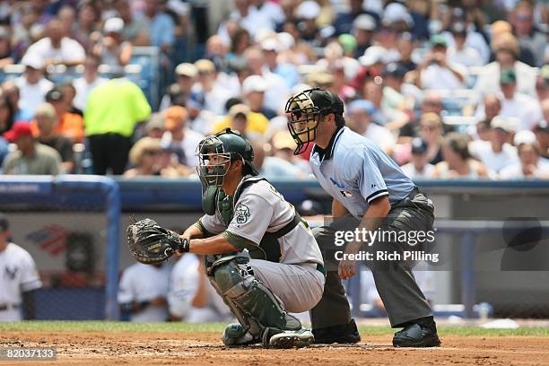 Kurt Suzuki of the Oakland Athletics and home-plate umpire James Hoye await a pitch during the game against the New York Yankees at Yankee Stadium in...