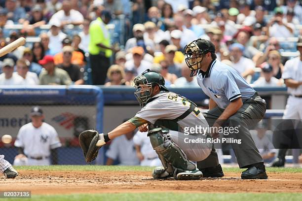 Kurt Suzuki of the Oakland Athletics and home-plate umpire James Hoye await a pitch during the game against the New York Yankees at Yankee Stadium in...
