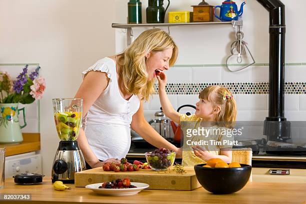 little girl helps her mother preparing fresh fruit smoothie. - pregnancy healthy eating stock pictures, royalty-free photos & images