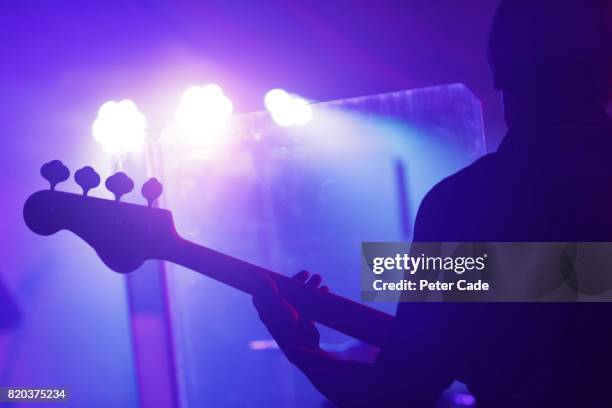 man playing guitar on stage - bassgitarre stock-fotos und bilder